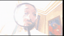 a man is looking through a magnifying glass at a painting