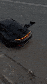 a car with a red tail light is driving down a highway next to a railing