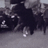 a group of people are dancing in a dark room in a tiktok video .