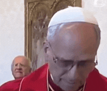 a bald man wearing glasses and a white hat looks down