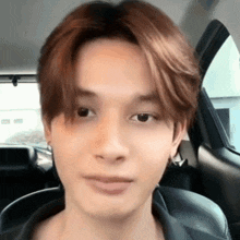 a young man is sitting in the back seat of a car and looking at the camera .