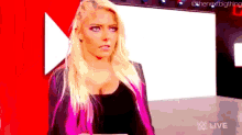 a woman with blonde hair and pink highlights is standing in front of a white wall .