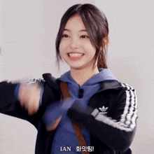a girl wearing an adidas jacket smiles and says ian