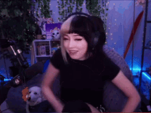 a woman wearing headphones and a black shirt is sitting in a room with a dog .