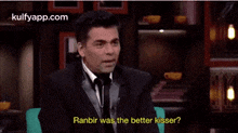 a man in a suit and tie is smiling and asking ranbir was the better kisser ?