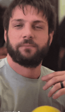 a man with a beard and a ring on his finger looks at the camera