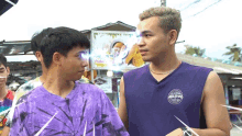 two men are standing next to each other and one has a purple tank top that says california