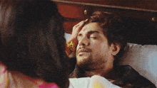 a woman in a pink saree is looking at a man in a bed .