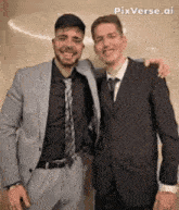 two men in suits and ties are posing for a photo
