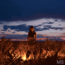 a woman is standing in a field of burning grass with the letters ms on the bottom