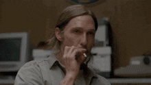 a man with long hair and a mustache is holding something in his mouth