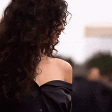a woman with curly hair is wearing a black shirt .