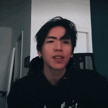 a young man in a black hoodie looks at the camera with his mouth open