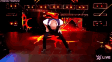 a man in a purple vest is dancing on a stage in front of a fire .