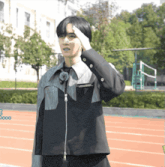 a man salutes while wearing a black jacket with a zipper on it