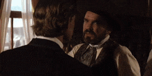 a man with a mustache is talking to another man with the words go ahead above him