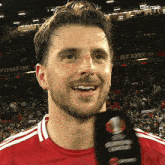 a man in a red shirt is holding a microphone in front of a crowd that says red army on the stands
