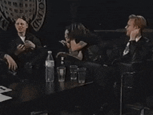 a group of people sitting around a table with a sign that says sound in the background