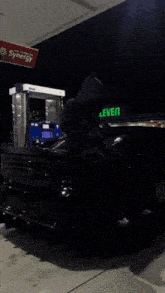 a black car is parked on a sidewalk at night