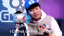 a man wearing a hat with the letter s on it is holding a stuffed animal and says i cannot confirm nor deny