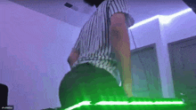 a man in a striped shirt is standing in front of a green light that says shuleythu