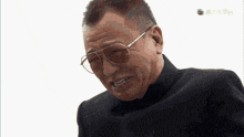 a man wearing sunglasses and a black suit is being shown on a tv screen