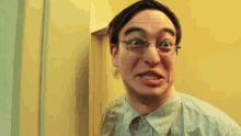 a man wearing glasses and a plaid shirt making a funny face