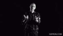 a man in a black jacket and black shirt is standing in the dark .