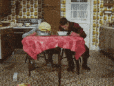 a man is sitting at a table with a red table cloth that says ' a ' on it