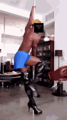 a man in blue shorts and black boots is dancing on a pole in a living room