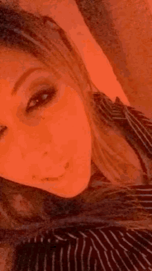 a close up of a woman 's face with a red background and a striped shirt .