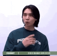 a young man with long hair is wearing a green sweatshirt and making a funny face .
