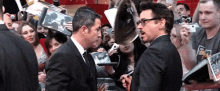 a man in a suit and tie is shaking hands with another man in front of a crowd .