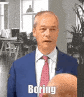 a bald man in a suit and tie is talking to another bald man in an office .