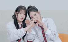 two girls are making a heart with their hands