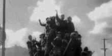 a black and white photo of a large group of people standing on top of a vehicle .