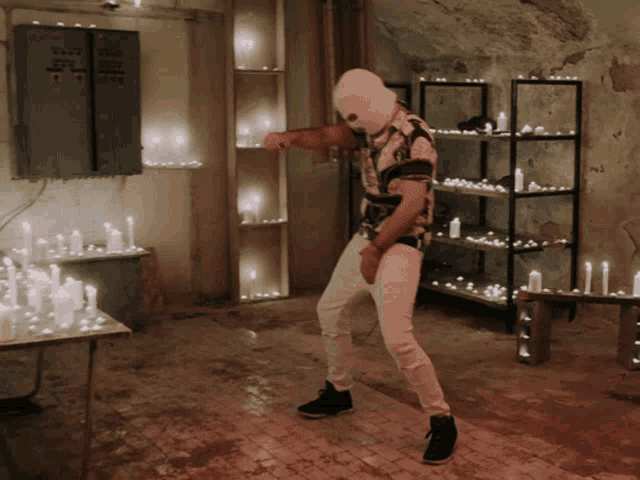 a man wearing a ski mask is dancing in a room with candles on shelves