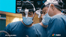 two surgeons are looking at each other in an operating room with nbc written on the bottom