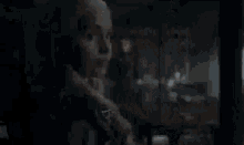 a man with a beard is standing in a dark room looking out a window .