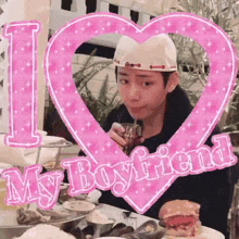 a man is sitting at a table drinking through a straw in front of a pink heart .