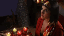 a woman sitting in front of a table with candles