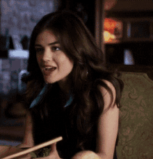 a woman is sitting on a couch with chopsticks in her hands
