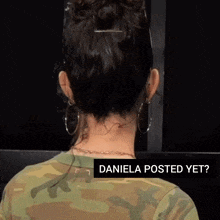 a woman wearing hoop earrings and a camouflage shirt says daniela posted yet ..