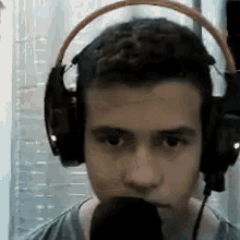 a man wearing headphones and a microphone is talking into a microphone .