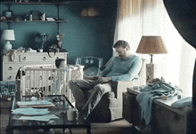 a man is sitting in a chair in front of a baby in a crib