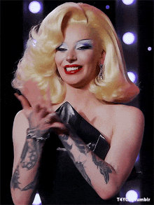 a woman with blonde hair and a tattoo on her arm is smiling and holding a black clutch