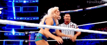 a woman is standing in a wrestling ring with a referee and the next big thing written on the bottom of the image