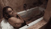 a man is laying in a bathtub with his arms around his neck