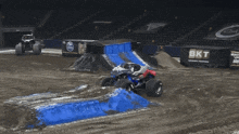 a monster truck is jumping over a ramp with a sign in the background that says the united game