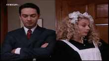 a man in a suit and tie stands next to a woman in a maid outfit on a television screen that says mega hd
